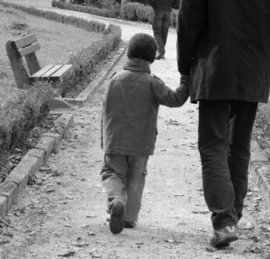 Black and white image; young child holds hand of adult